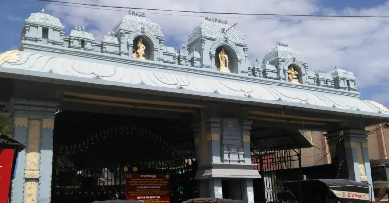 A broad gateway with small towers above, each niche holding a golden figure, and an iron gate below.