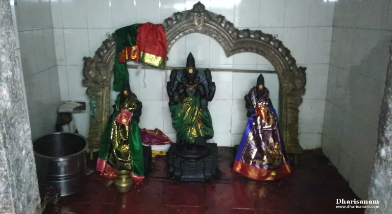Three draped idols under a stone arch, central figure flanked by two