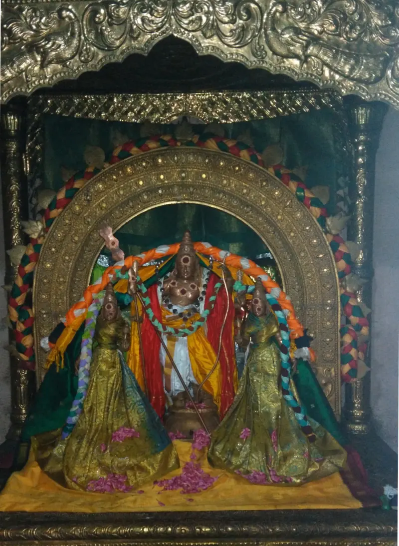 Garlanded image in a gold arch, flanked by two figures in green and gold cloth with flowers