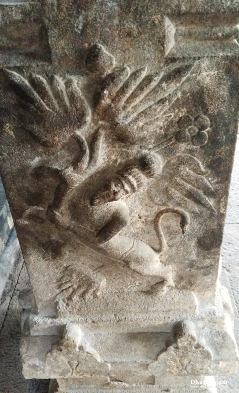 Pillar relief of a bearded face on an animal body, with large spread wings and a tail