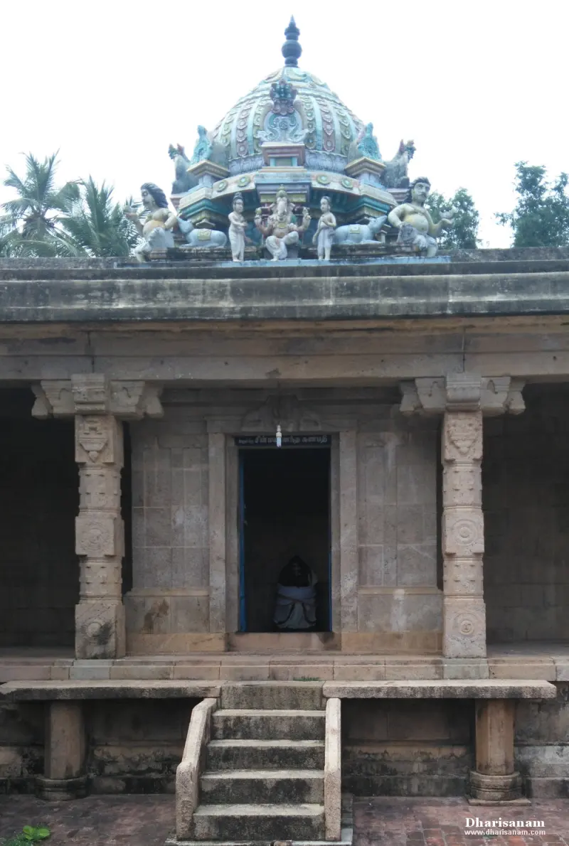 A stone porch with steps leads to a doorway, with painted figures and bulls on the tower above and palms behind