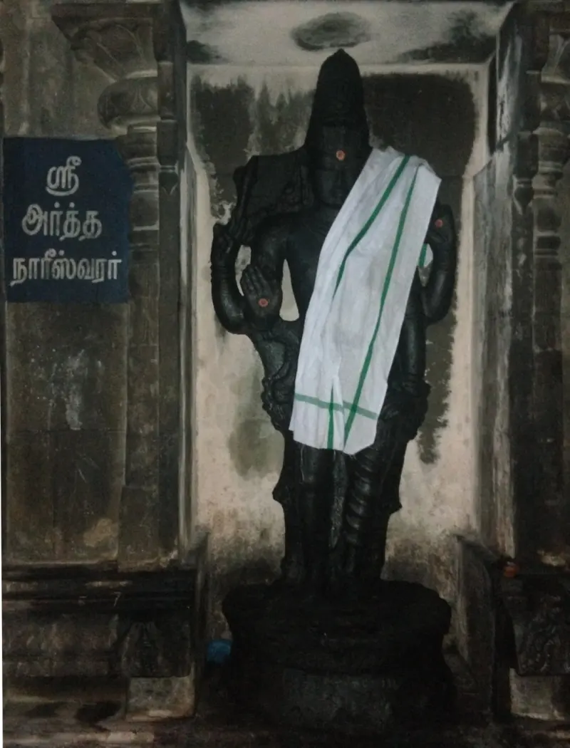 A dark standing figure in a niche with a white cloth over one shoulder