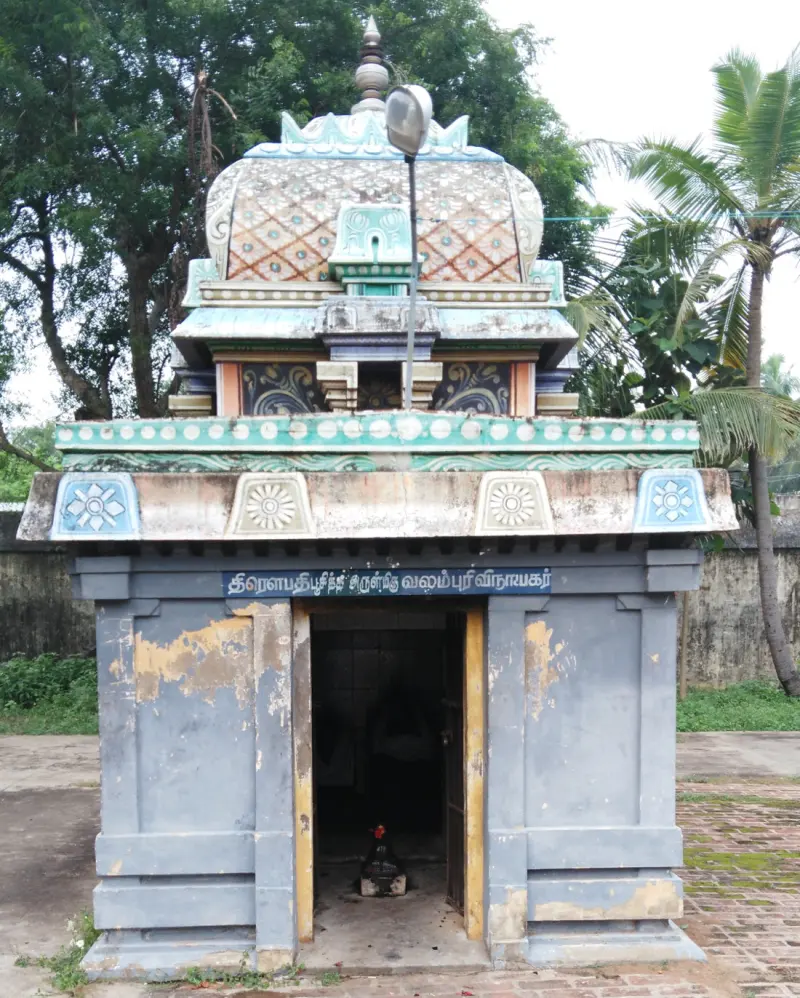 A small shrine with a domed tower and a Tamil board