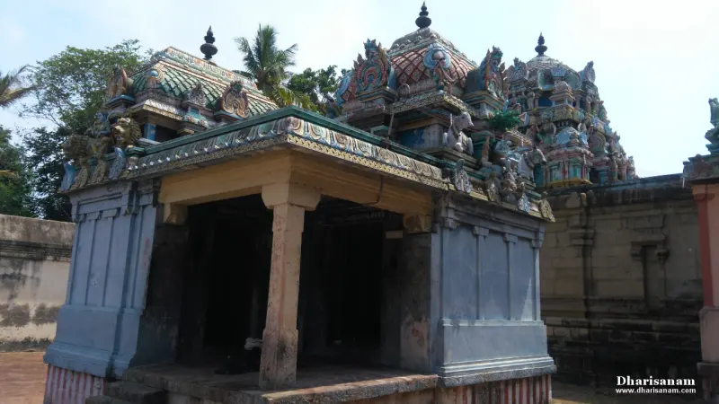 Open shrine with a pillar and a carved roof, with tiered domes rising behind