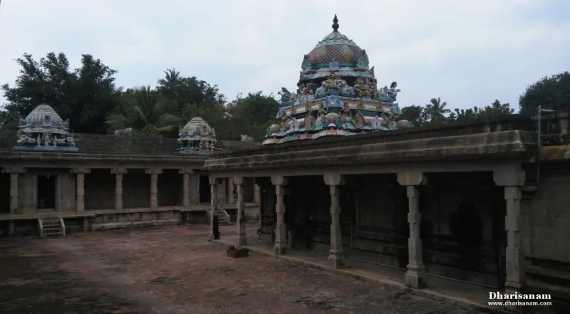 A paved courtyard with a pillared corridor on the right, a painted tower above it and two more towers behind