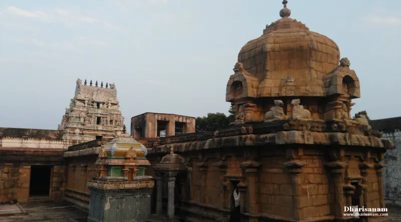 A domed tower built of stone blocks with bull figures at its corners, a colourful small shrine in front