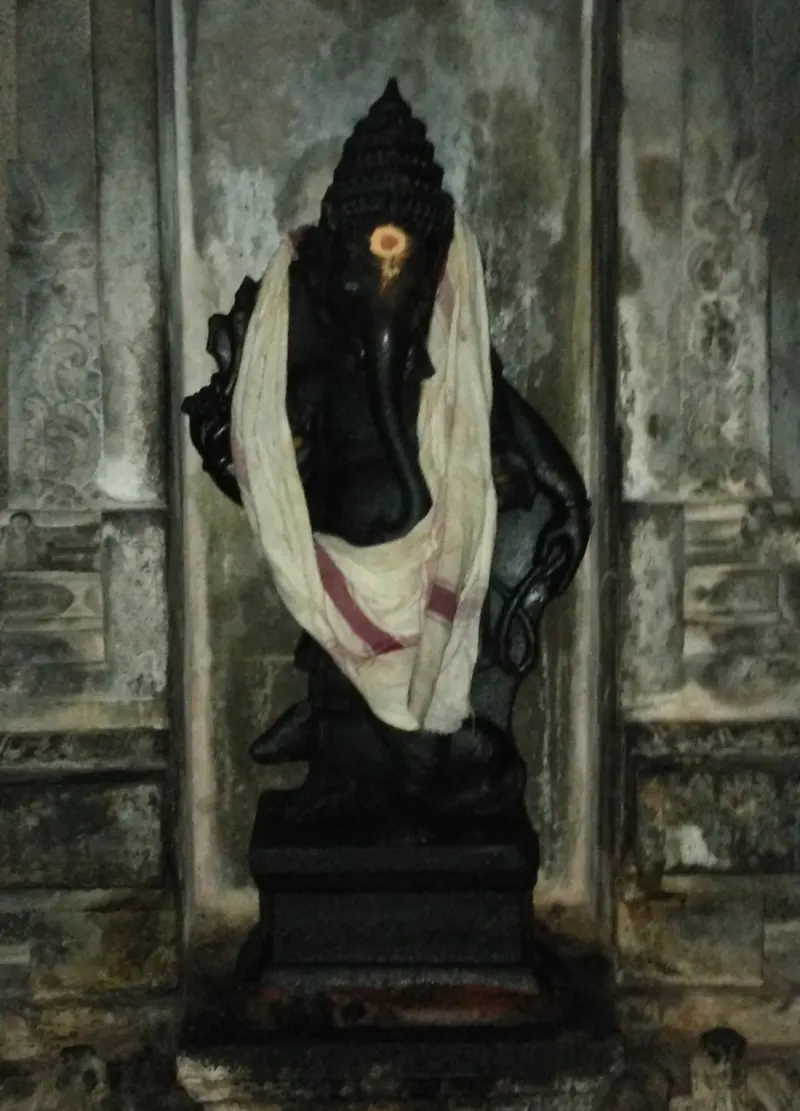 A dark stone figure draped in cloth, in a wall niche