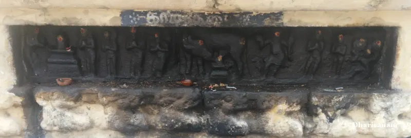 Long blackened stone relief showing standing figures with lamps below