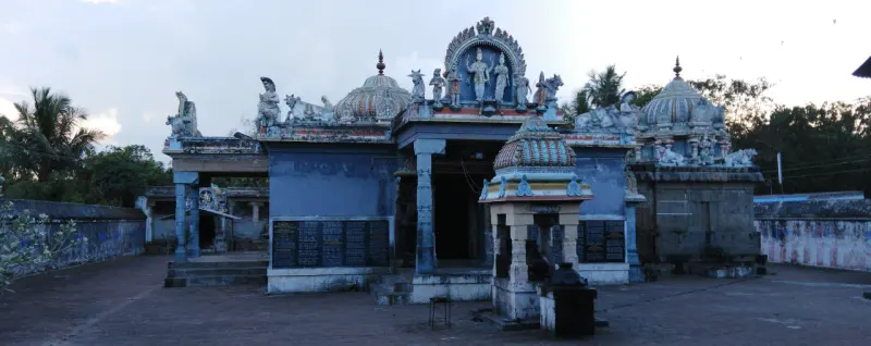 Blue-painted sanctum with a small canopy shrine in front, in a paved courtyard