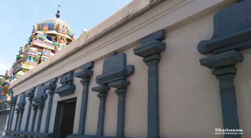 A cream wall with grey pilasters and a painted tower rising behind it at upper left