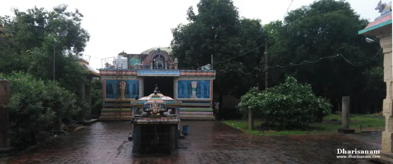 Small shrine in a paved courtyard, with a painted hall and trees behind it