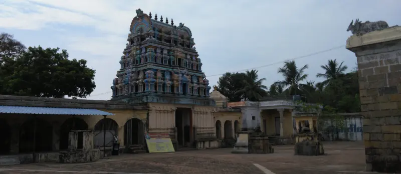 A tiled gopuram stands above the entrance, with the courtyard and corridor in front