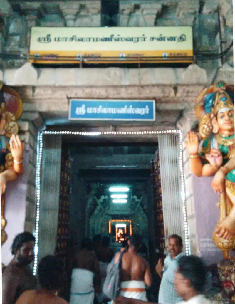 Devotees stand before a bright doorway with a Tamil board naming the Masilamaneeswarar shrine