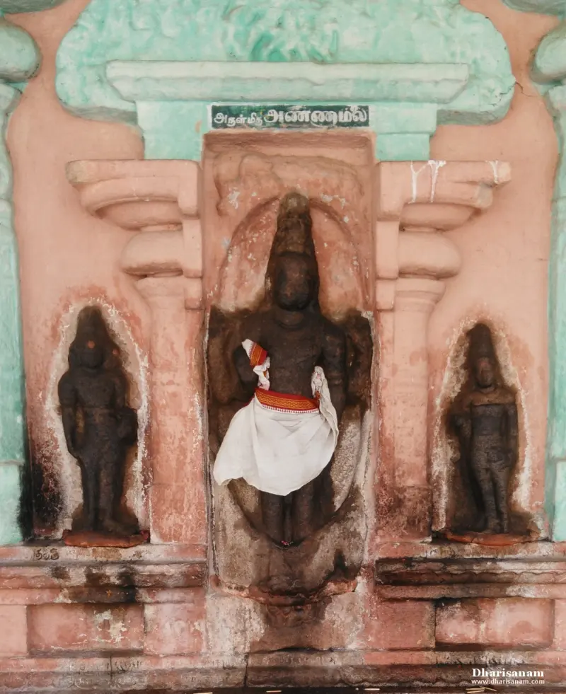 A standing image in white cloth in a niche, with a smaller image in a niche on each side