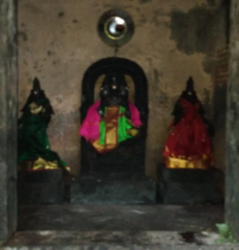 Three small dressed figures in a dim niche, the centre one under an arch