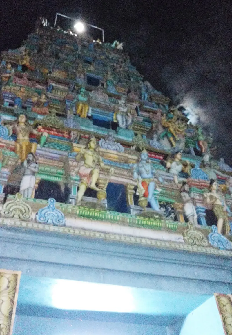 Looking up at a tower with tiers of brightly painted figures against the night sky