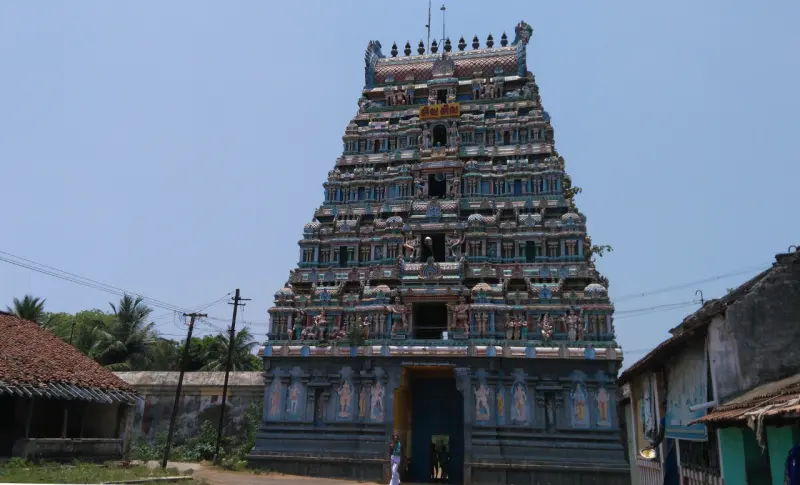 The tall painted Rajagopuram with its open entrance at the base, seen against a clear sky.