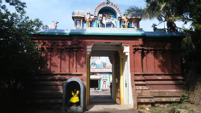 The red entrance arch with sculptures above and a side niche