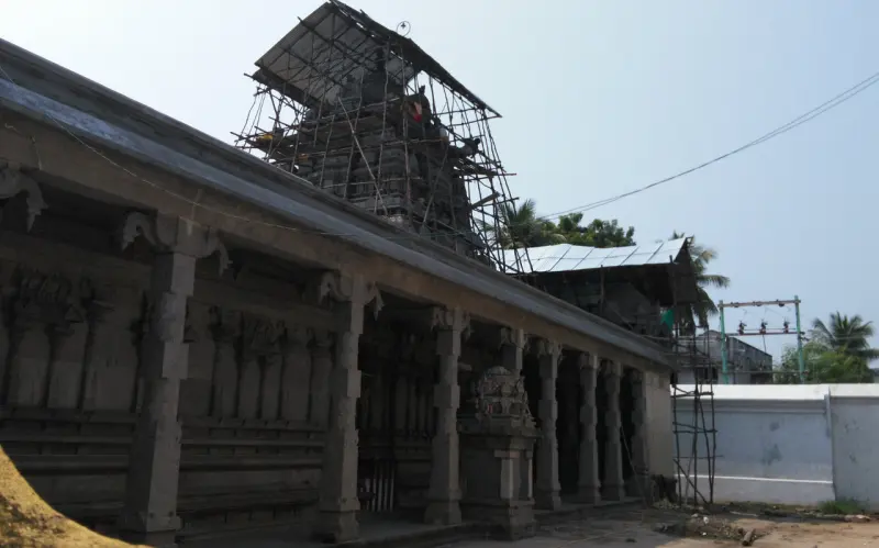 A stone corridor with scaffolding around the inner tower and a white compound wall to the right