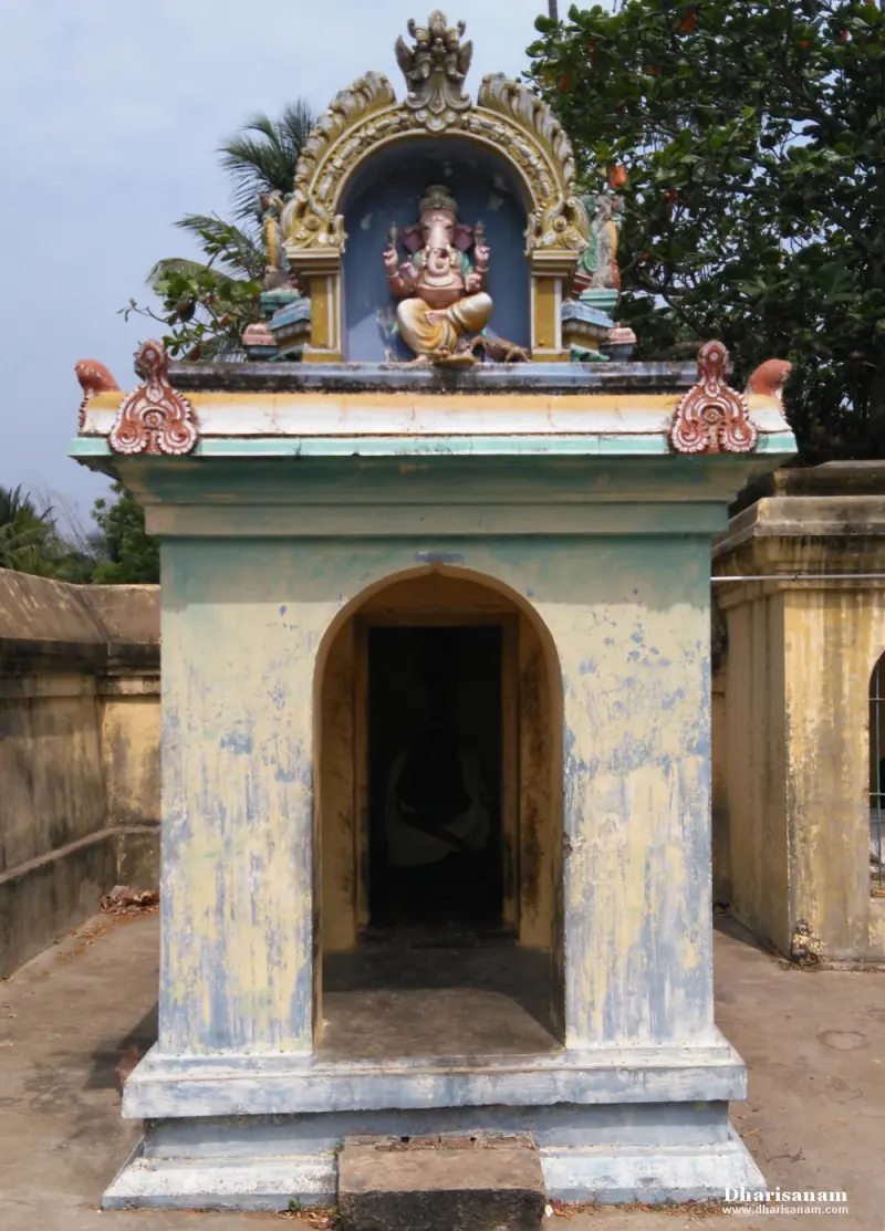 Small shrine with a painted Vinayakar above an arched doorway, with trees behind