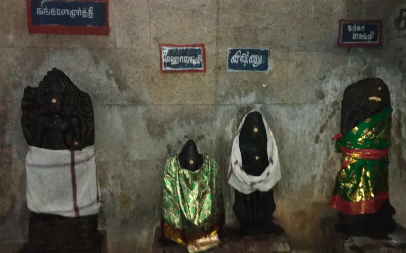 Four small stone idols in cloth, with name boards above