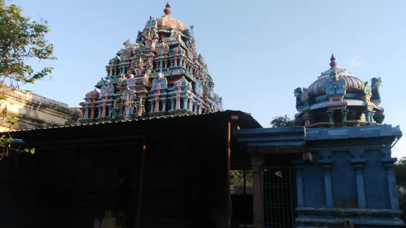 A tall colourful tower with sculpted figures beside a smaller domed tower, under a clear blue sky.