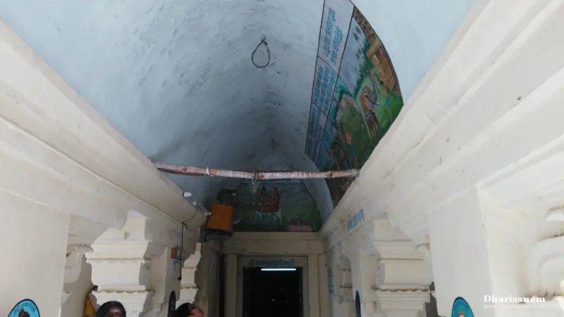 Curved white ceiling with colourful paintings on its right side, and a doorway at the far end