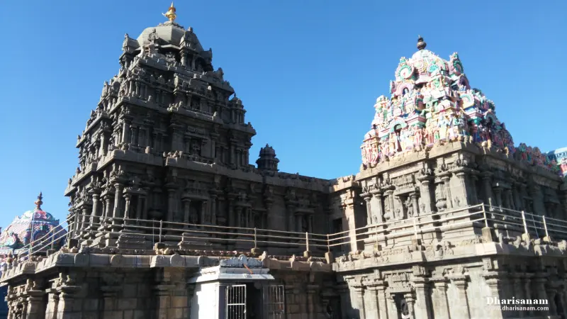 A dark granite tower and a smaller painted tower side by side on the sanctum roof.