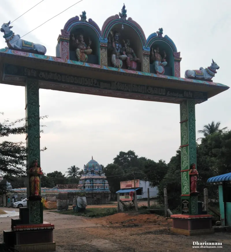 A painted arch gateway with Nandhi figures on top and sculpted deities in its niches, the temple tower behind.