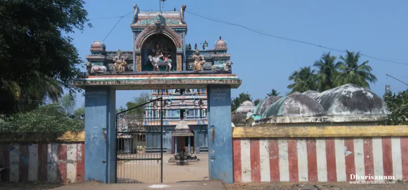 A blue gateway with a sculpted arch, an open gate, and the tower seen beyond a striped wall