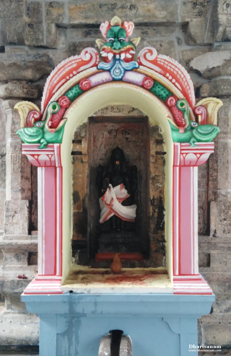 A dark image in white cloth inside a niche framed by a pink and green arch