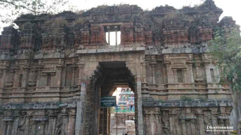 Dark weathered stone gateway with carved walls and an opening in the upper part, with an arched passage