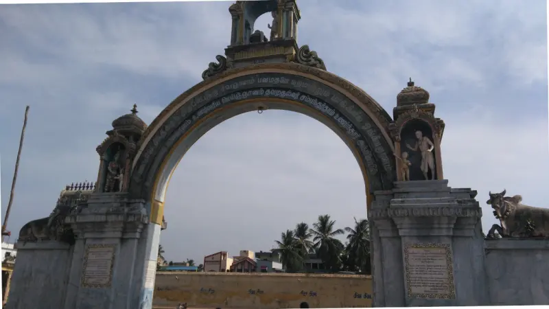 A large stone arch with a line of Tamil lettering, a bull on one side and figures in niches
