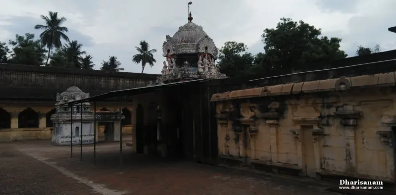 A carved stone tower rises over a covered entrance, with palm trees and a pillared hall beside it.
