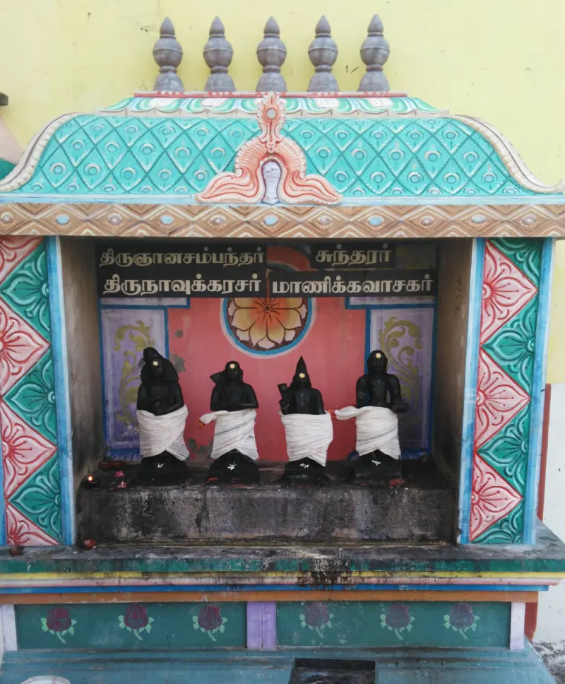 Four black Nalvar idols draped white under their name board