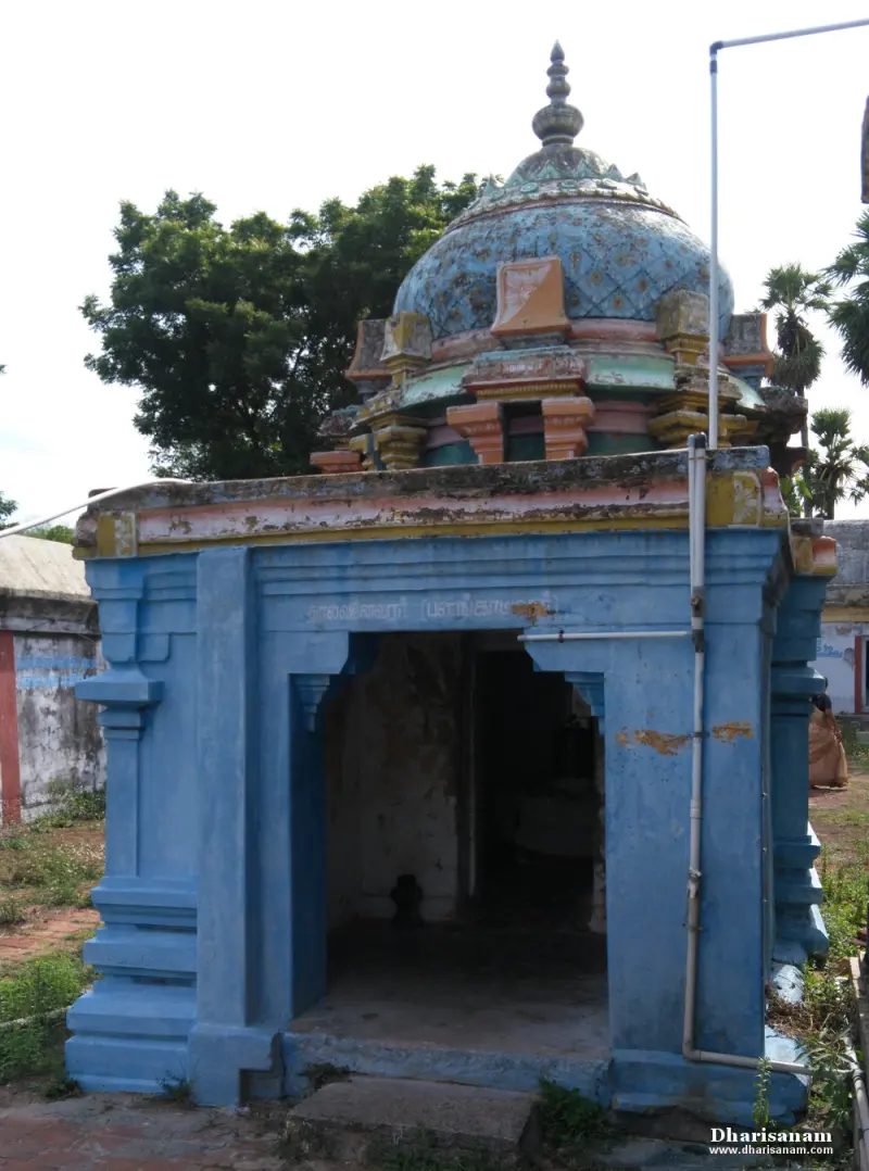 Small blue shrine with an open front and a painted dome on top, with trees behind
