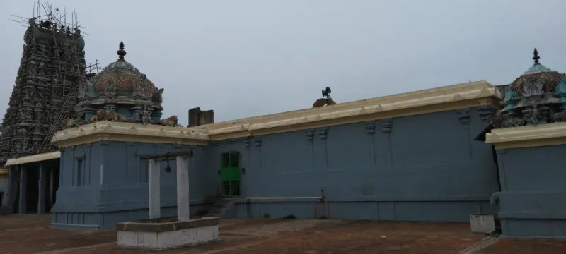 A long grey wall with a cream cornice, a small well canopy in front and the tower under repair at left.
