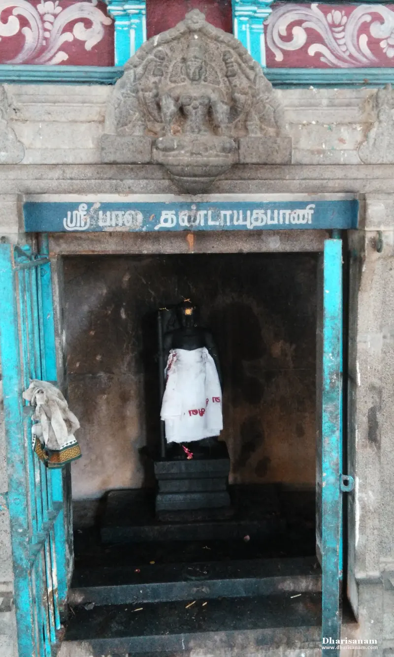 Standing idol draped in white cloth inside a small blue-doored shrine