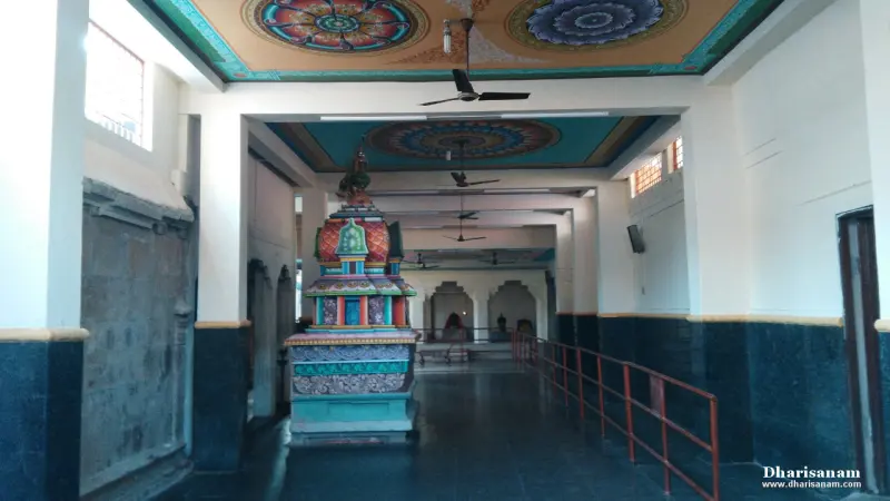 A wide hall with a painted ceiling, ceiling fans and a small decorated structure on the left