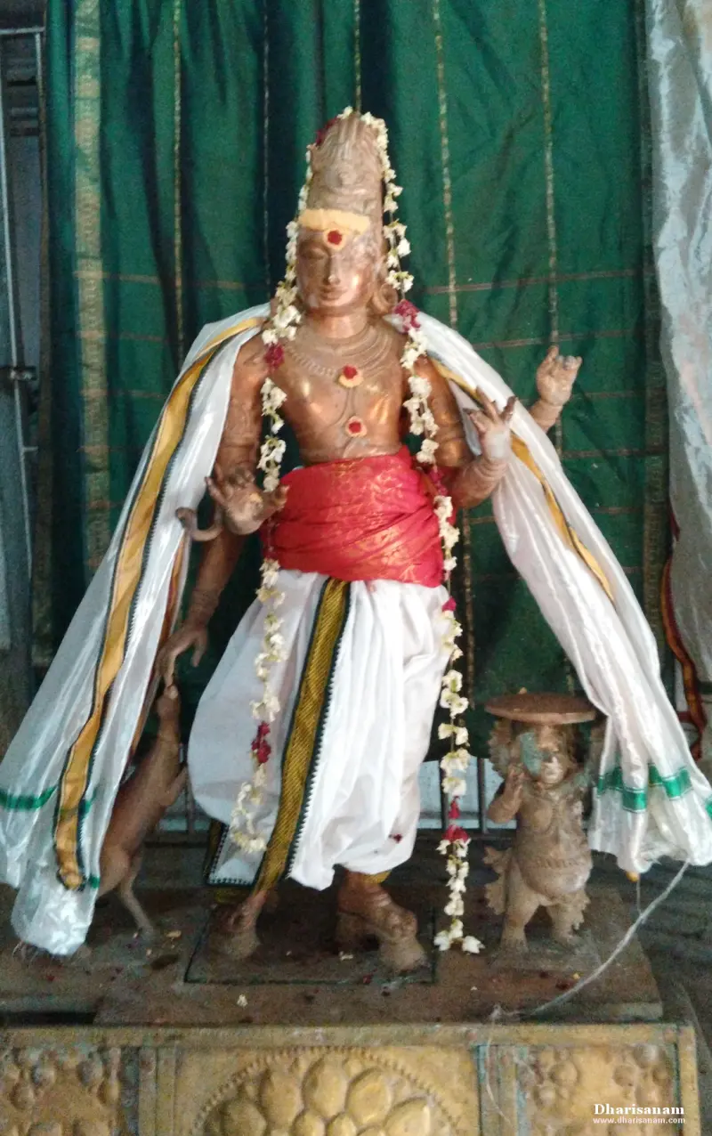 A bronze standing figure with several arms in white cloth, jasmine garlands, a deer at the leg, on a stone base