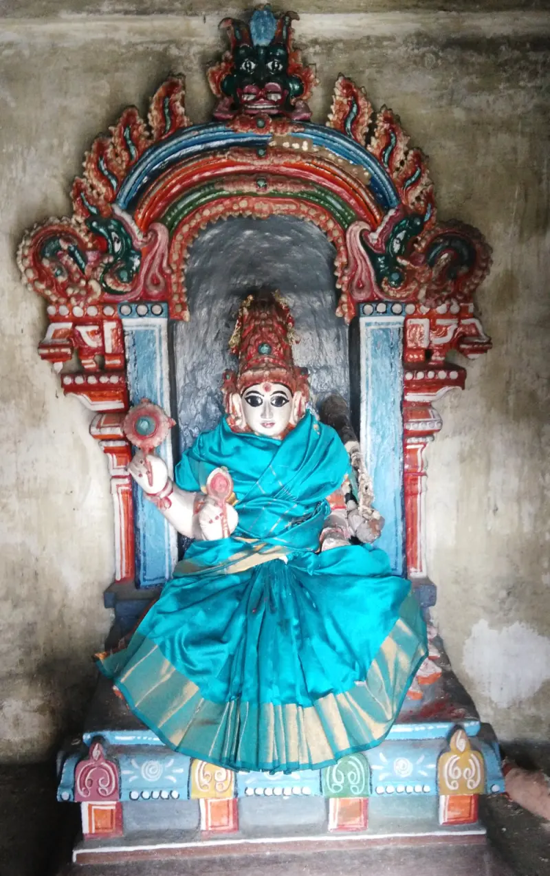 Seated goddess in a turquoise sari under a painted arch