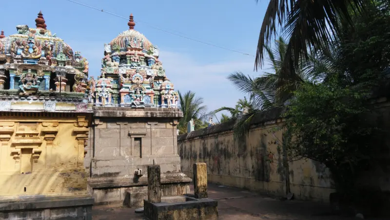 Two painted towers rise above stone and yellow walls, with a tree on the right