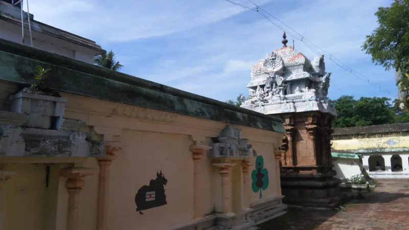 A plain corridor wall with Nandi paintings and a vimana behind