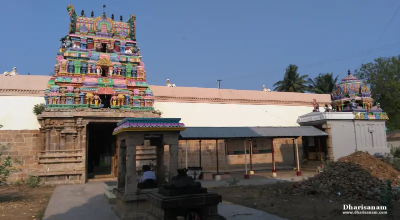 Painted gateway tower above a white outer wall, with a small shrine on the right