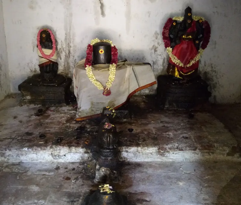 A garlanded lingam in the middle with a smaller image on each side, on a stone platform