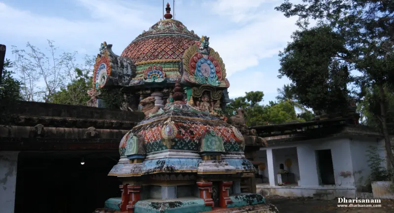 A close view of a domed tower with painted figures and a small shrine roof in front of it