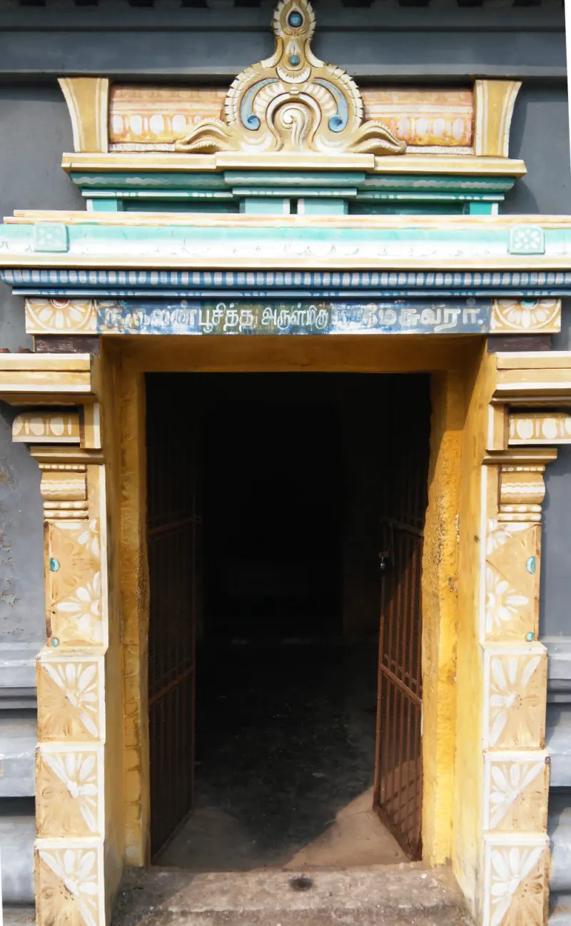A yellow painted doorway with a Tamil name board above