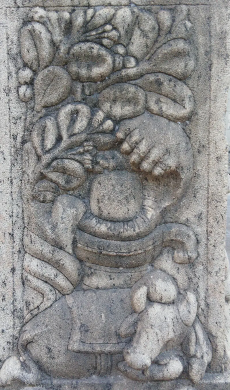 Stone relief of leafy branches, a fruit and a small animal on a pillar