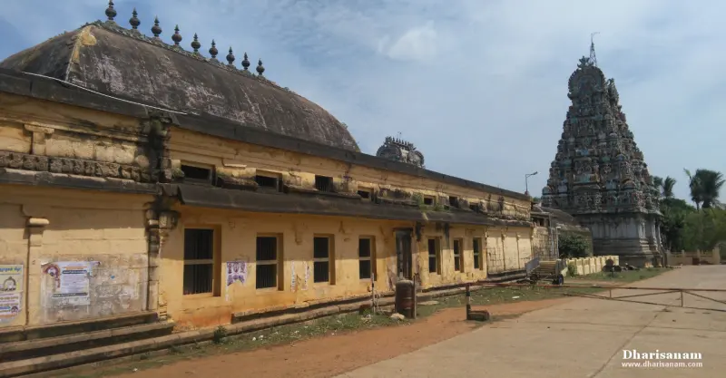 A long yellow-walled hall with a curved roof, and a dark tower on the right