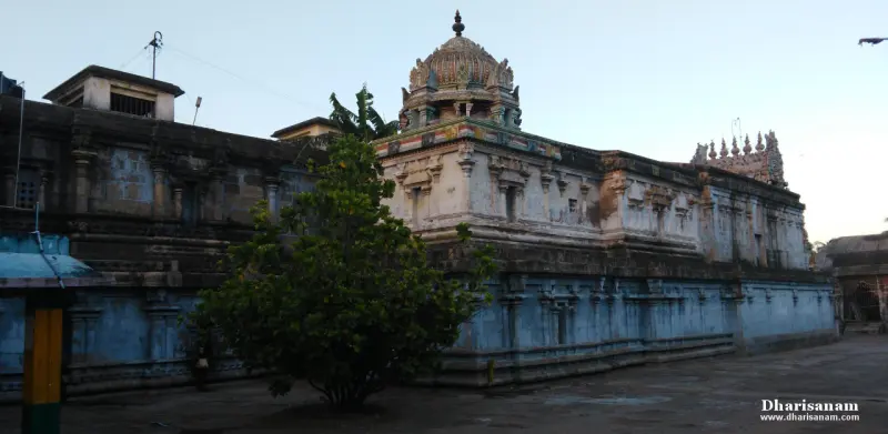 Blue-grey stone walls with a domed tower stand over a paved courtyard with a small tree at the front